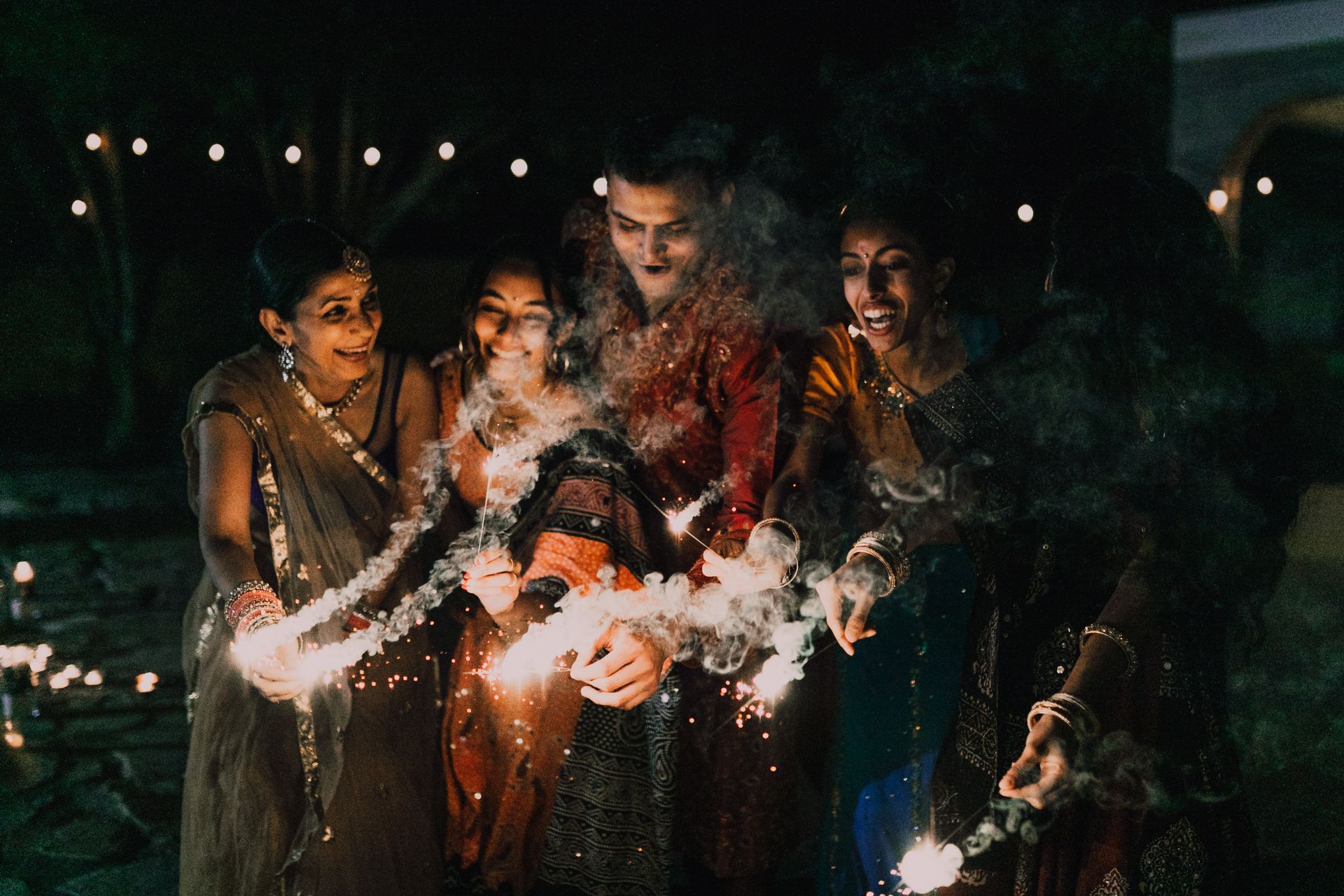 A family celebrating Diwali with sparklers at night.