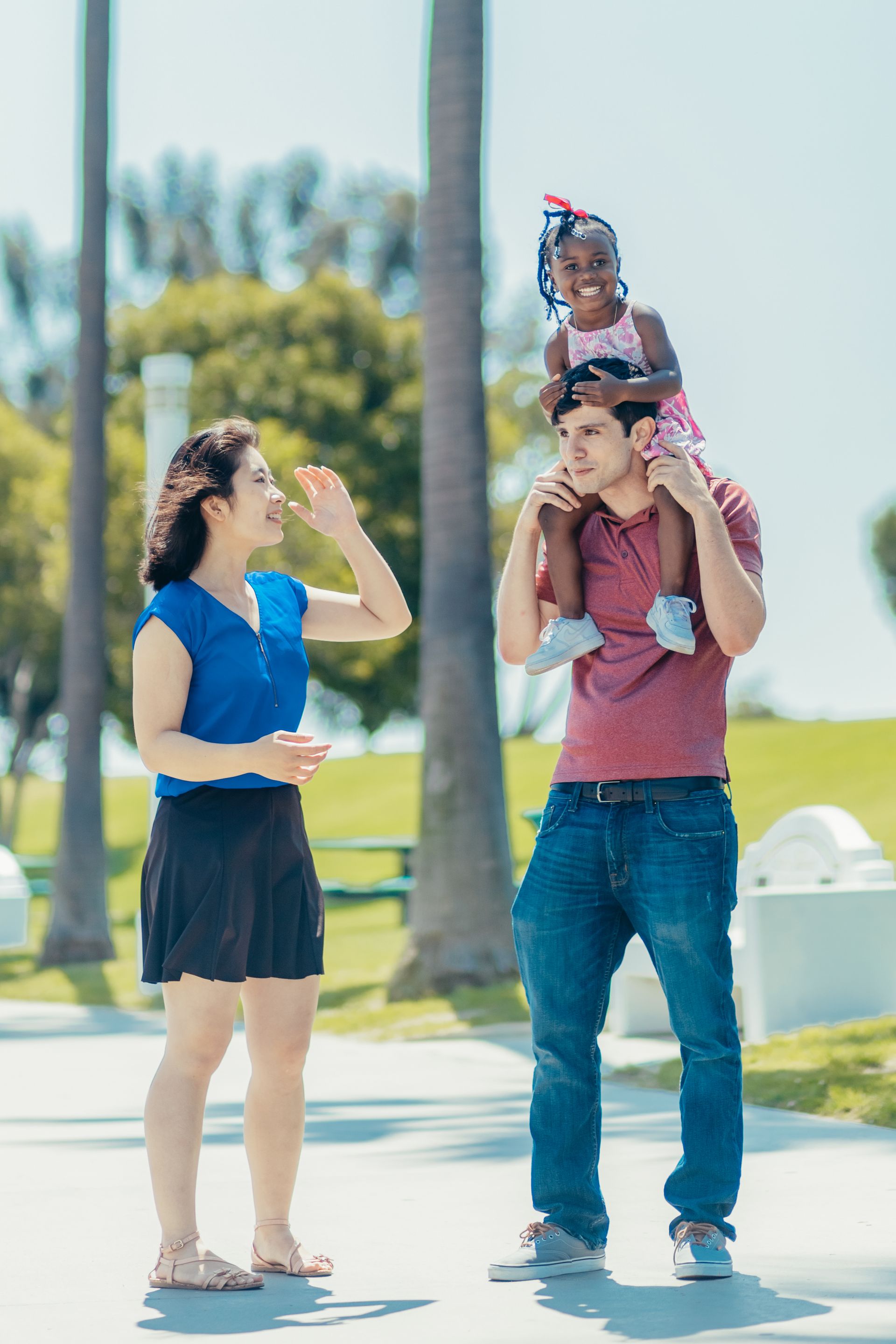 A multicultural family laughing together outdoors.