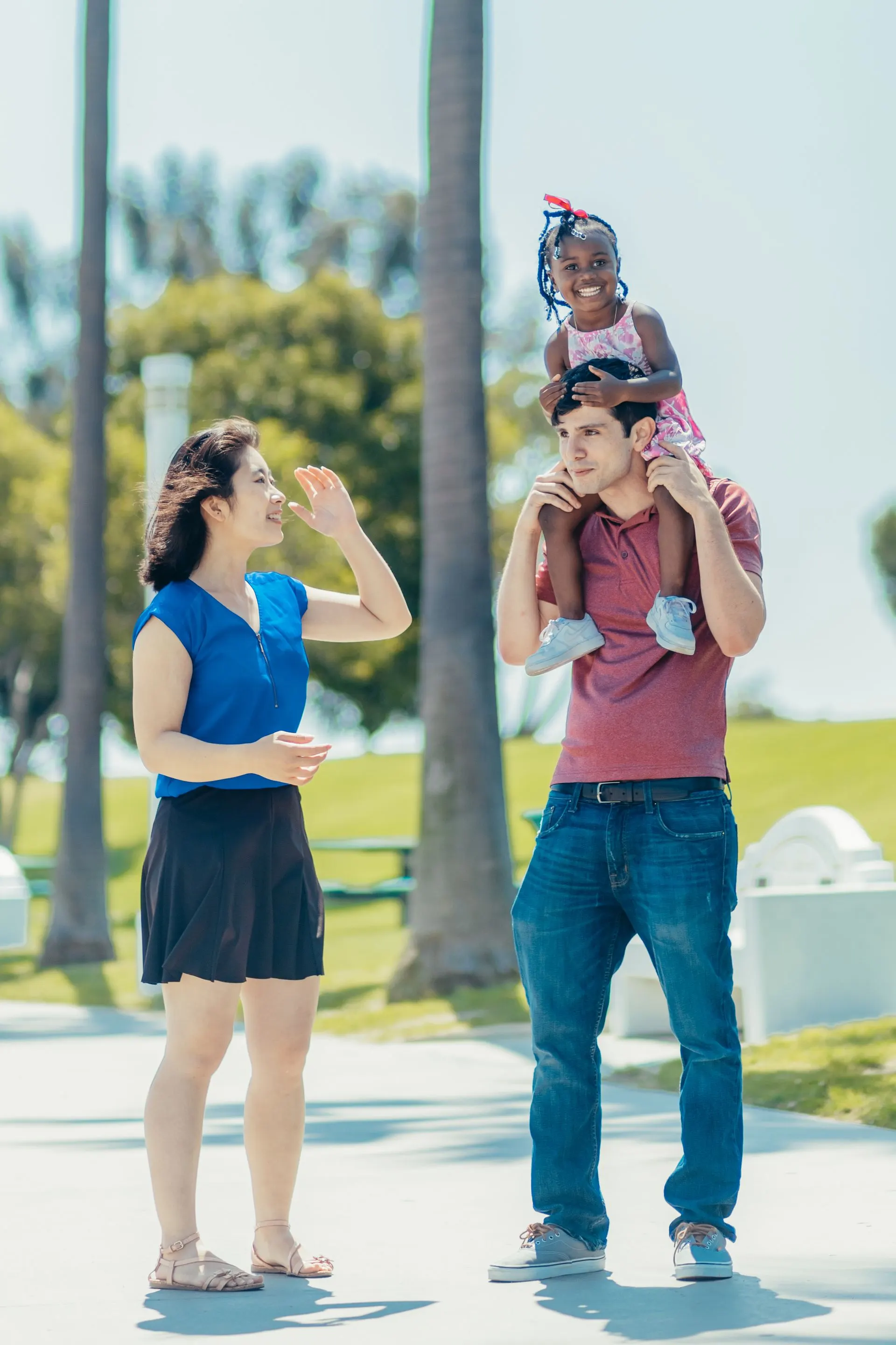 A multicultural family laughing together outdoors.